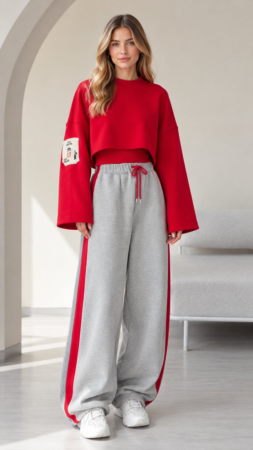 Front view of model wearing red cropped sweatshirt and grey wide leg sweatpants with red side stripe