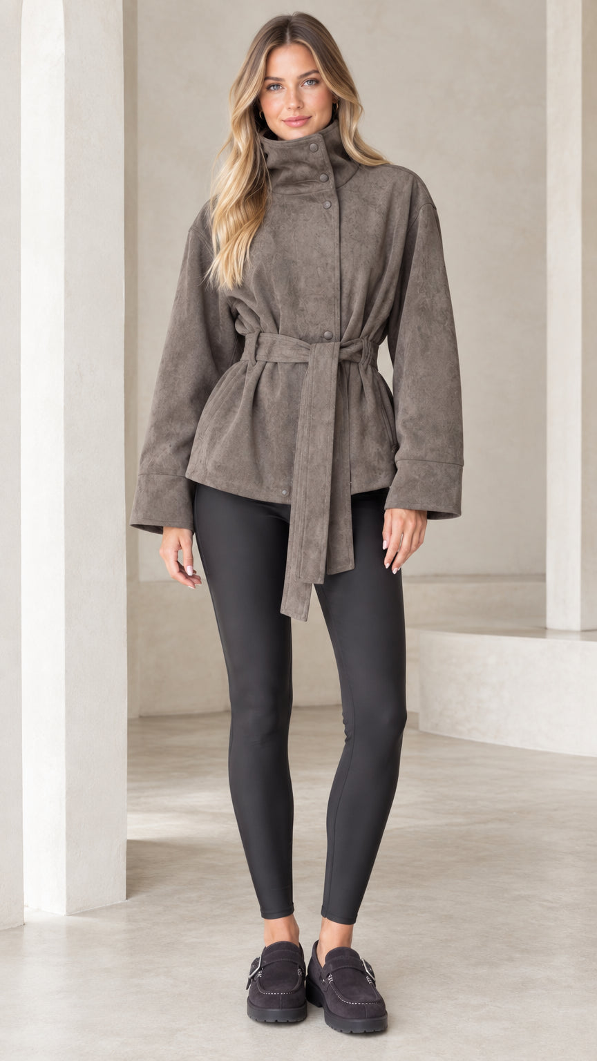 Front view of model wearing taupe high-neck belted faux suede jacket with black leggings