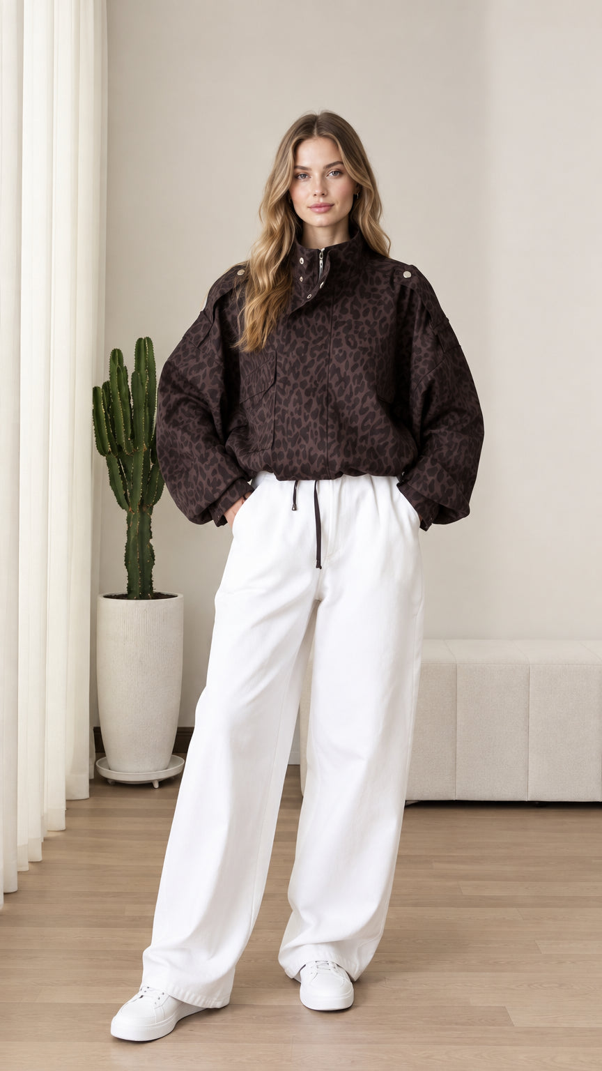 Front view of model wearing chocolate brown leopard print half-zip pullover jacket with white wide-leg pants