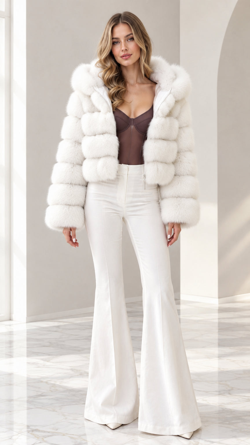Front view of model wearing white cropped hooded faux fur jacket with white flare pants