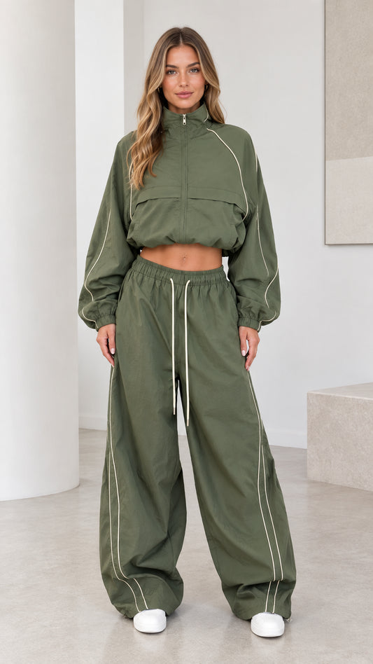 Front view of model wearing olive green cropped windbreaker jacket and wide leg parachute pants set