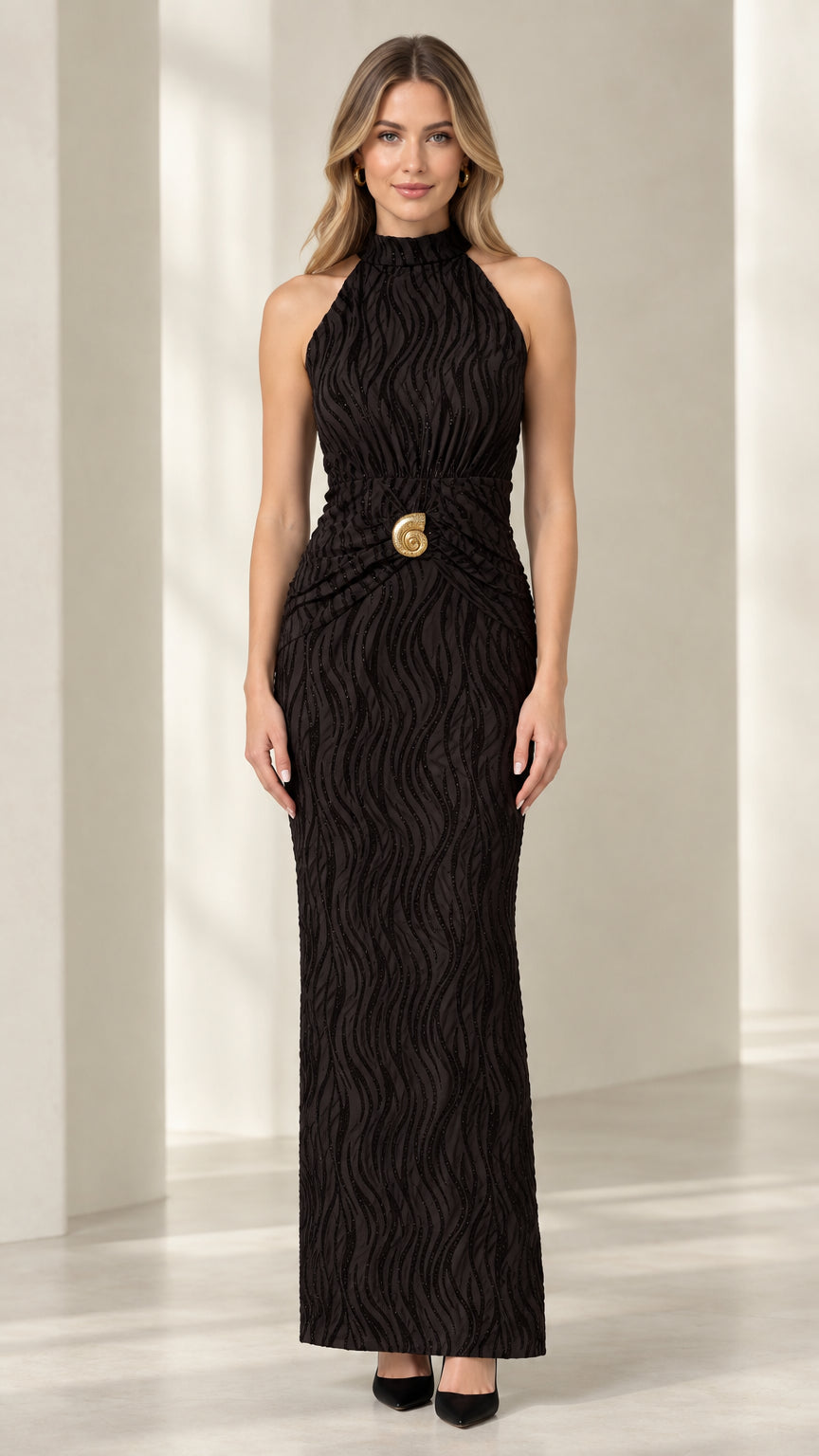 Front view of woman wearing black textured halter maxi dress with gold waist brooch
