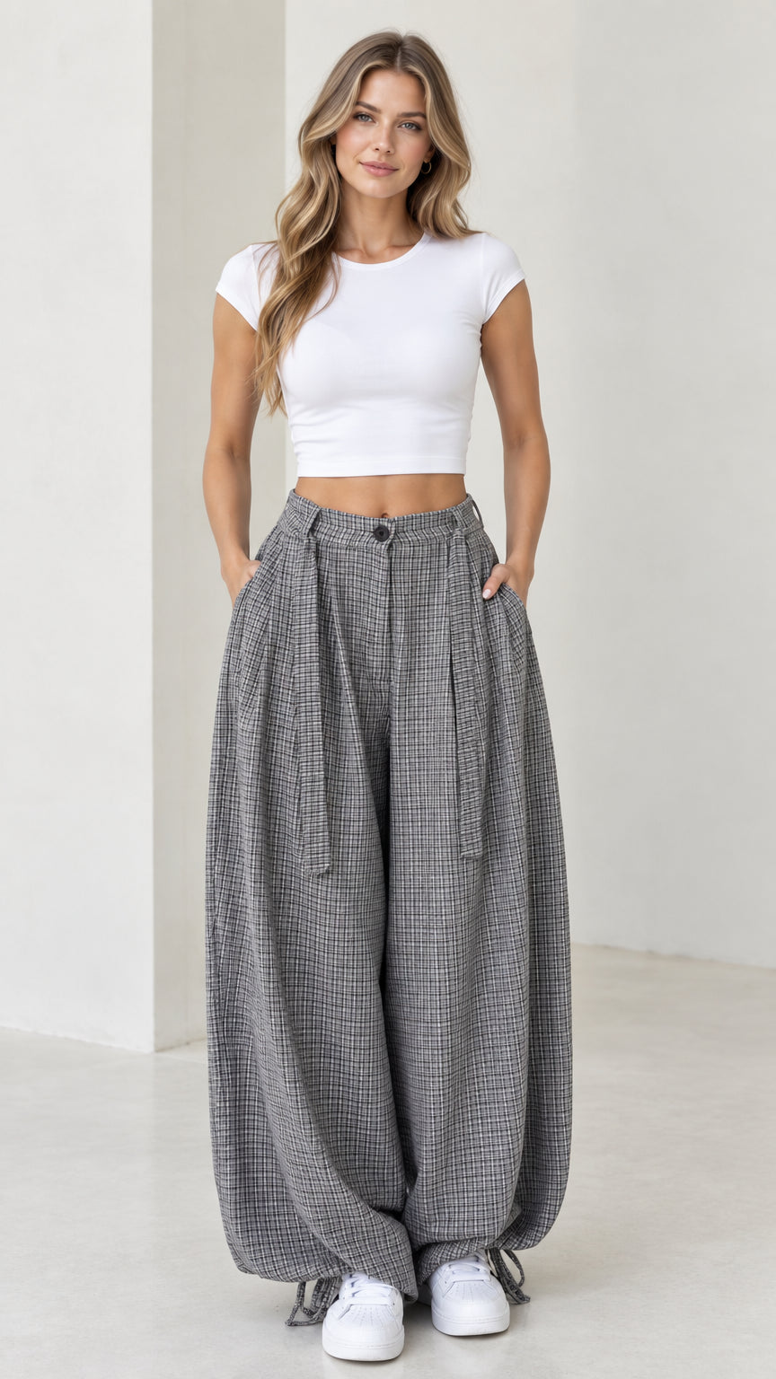 Front view of woman wearing grey micro-plaid pleated balloon pants with white crop top