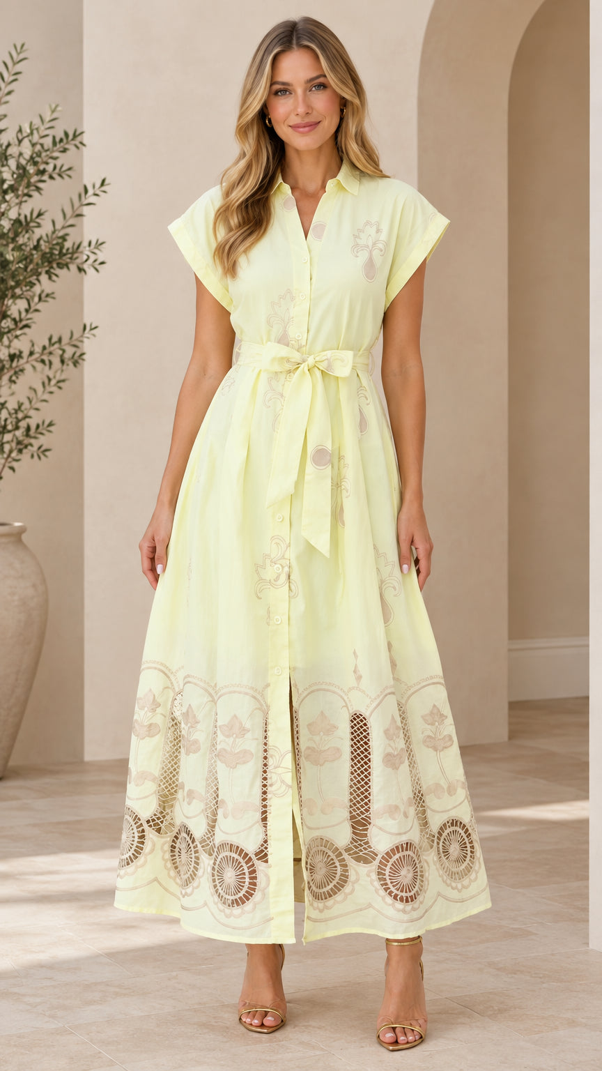 Front full-length view of woman wearing pale yellow embroidered button-down maxi shirt dress with tie belt