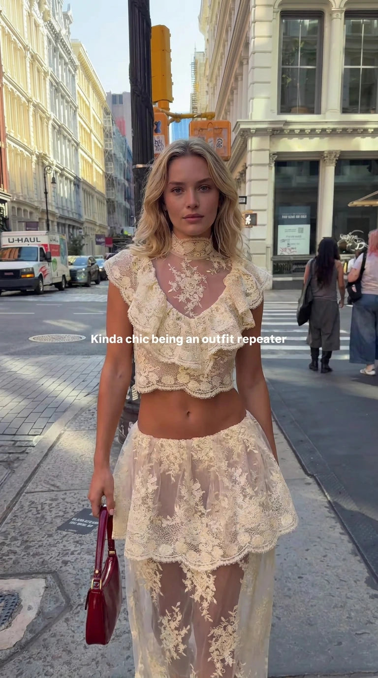 Full front view of model wearing cream floral lace ruffled crop top and tiered maxi skirt set on city street