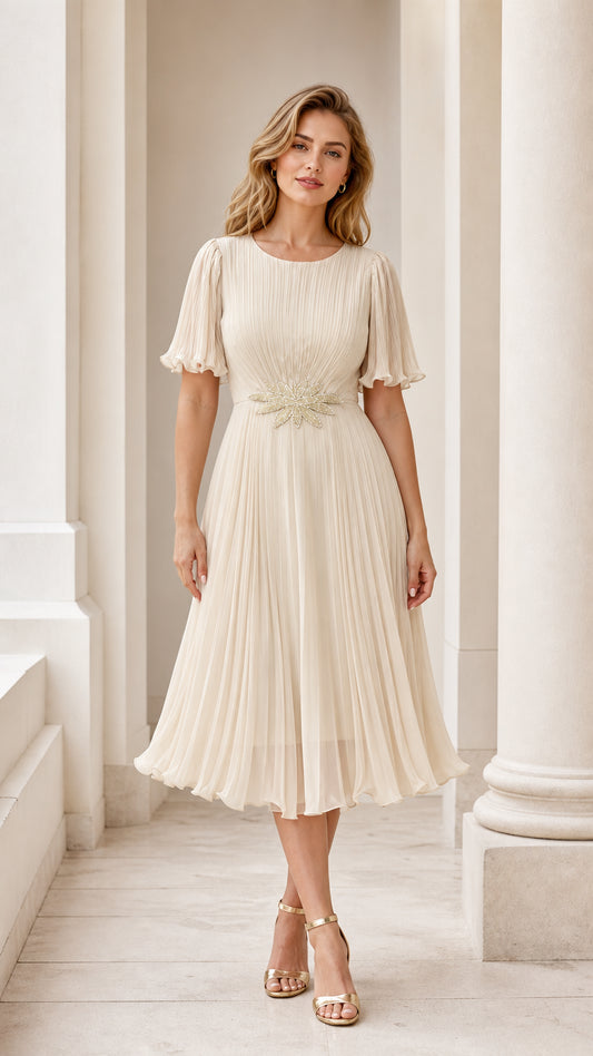 Front view of model wearing the champagne pleated midi dress with embroidered waist