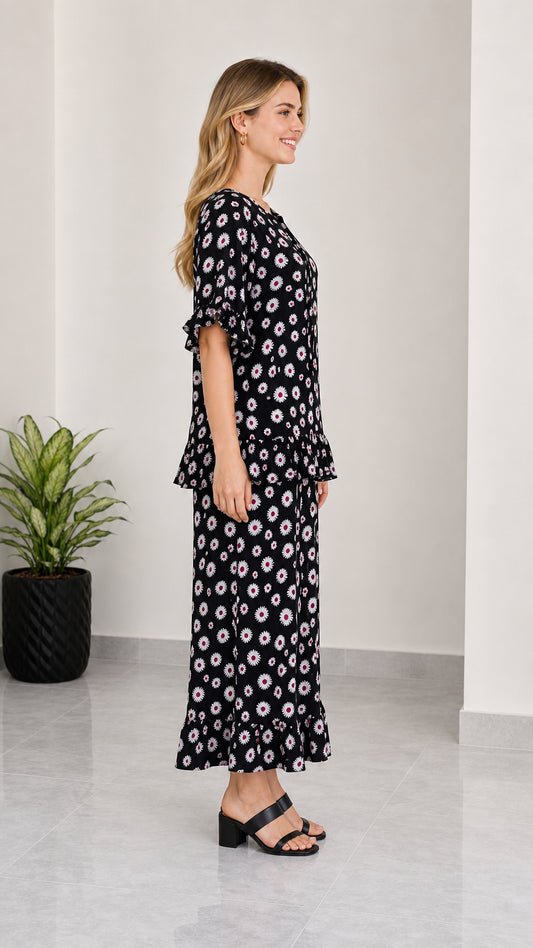 Side profile view of women's black floral matching top and maxi skirt set