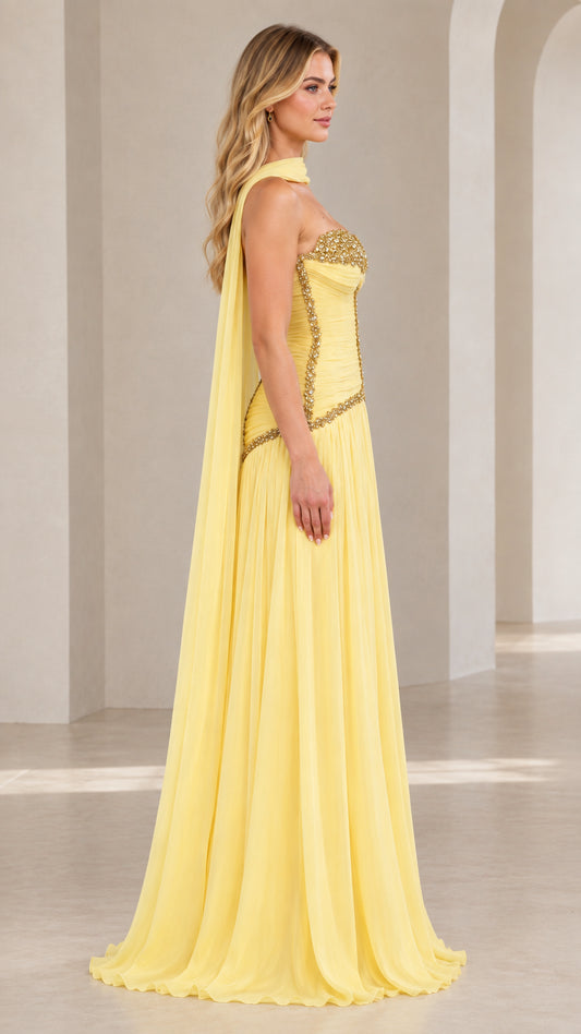 Side profile view of model wearing pastel yellow formal chiffon gown with draped neck scarf