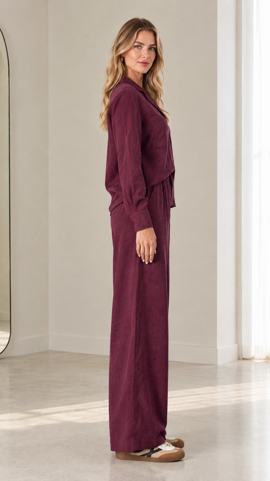 Side profile of model in relaxed-fit burgundy matching long-sleeve shirt and trouser set