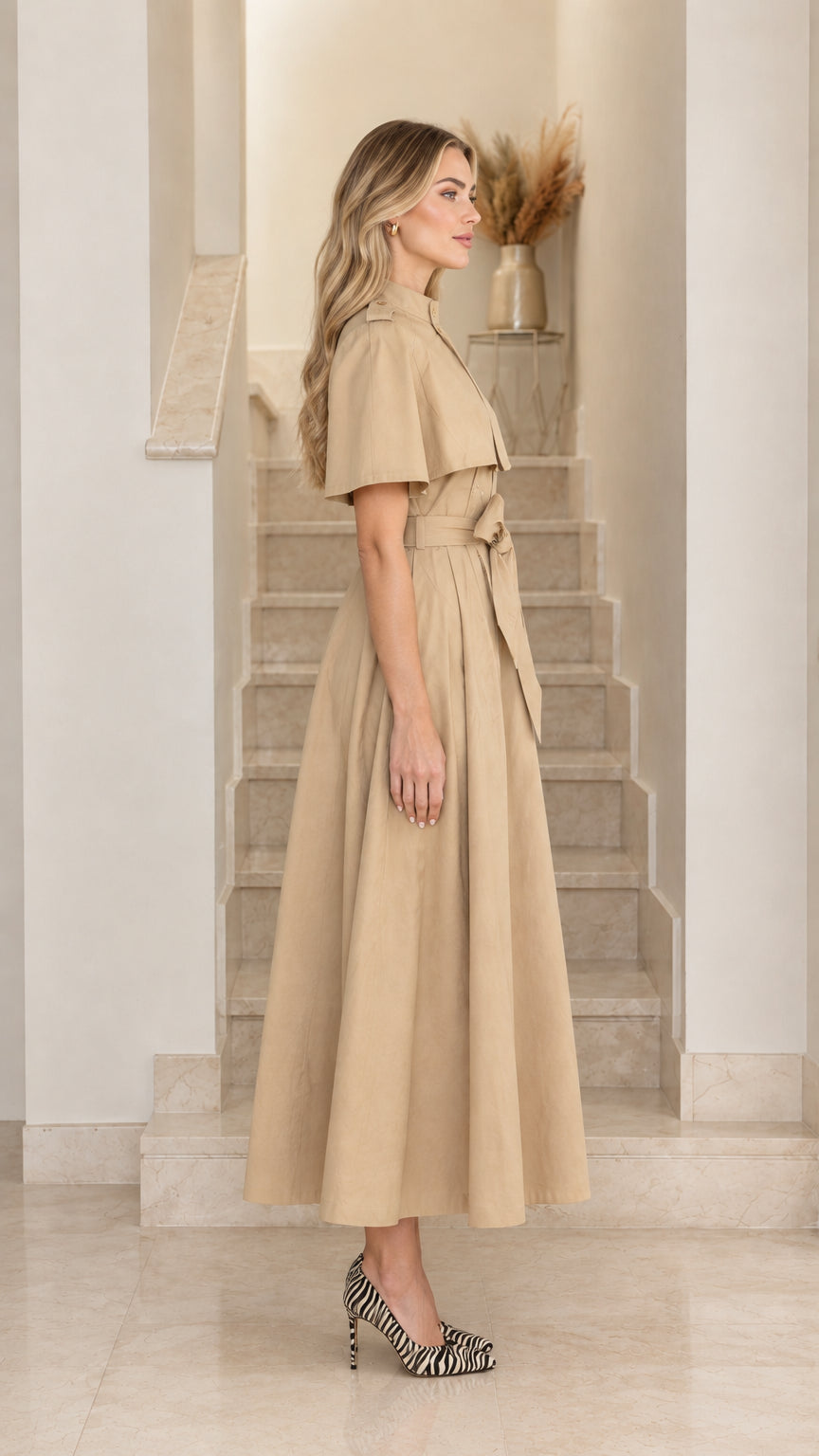 Side view of model wearing khaki capelet midi trench dress