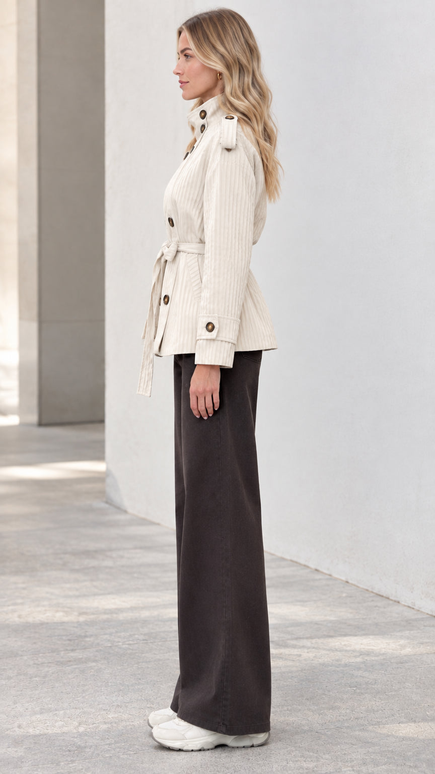 Side profile of model wearing cream belted stand-collar short jacket