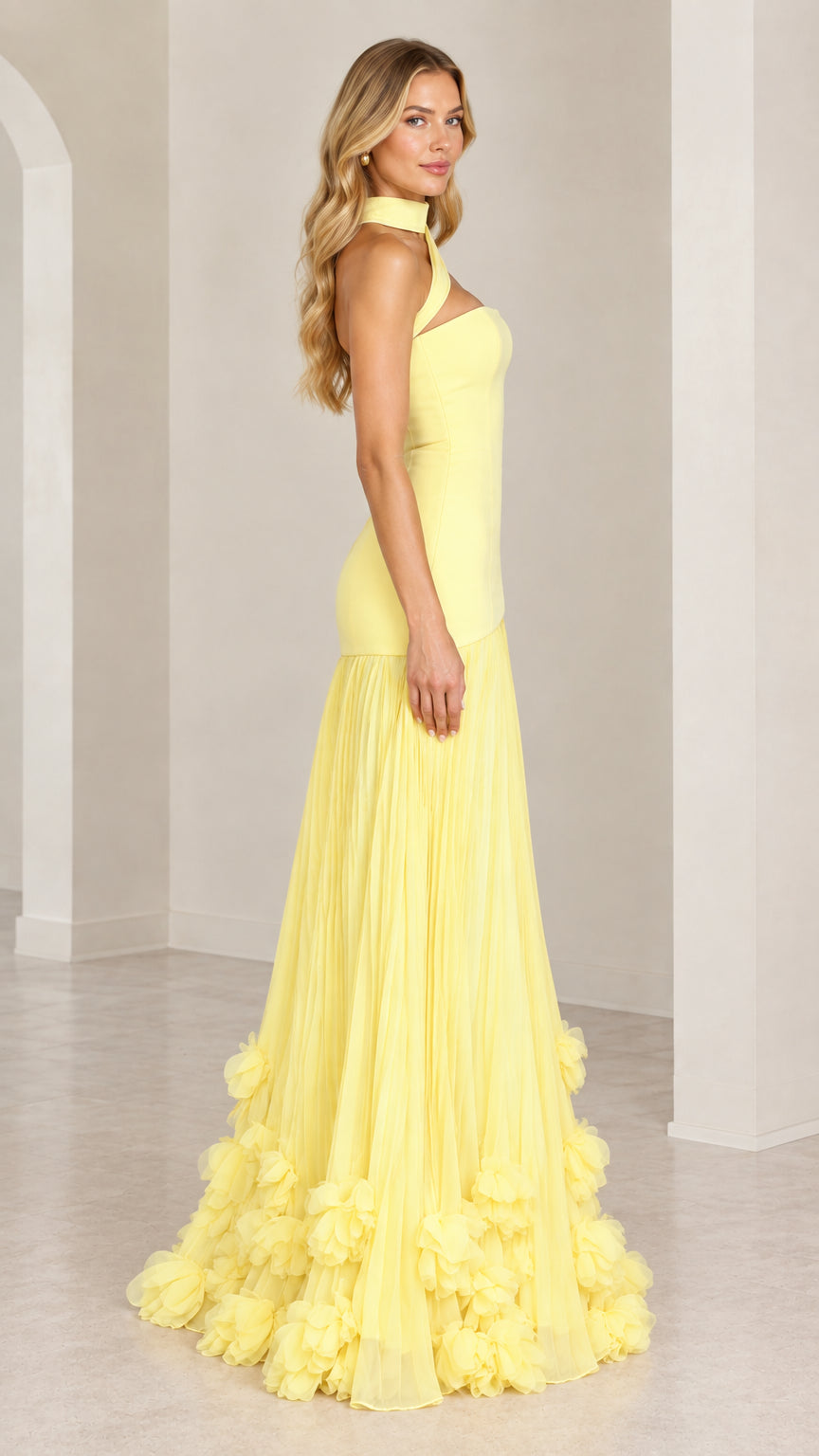 Side angle view of the yellow drop-waist maxi gown with rosette hem