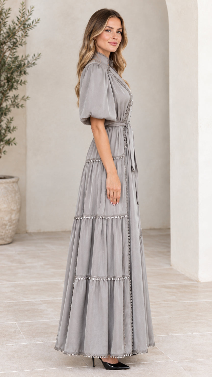 Side profile view of woman modeling grey tiered maxi dress with puff sleeves
