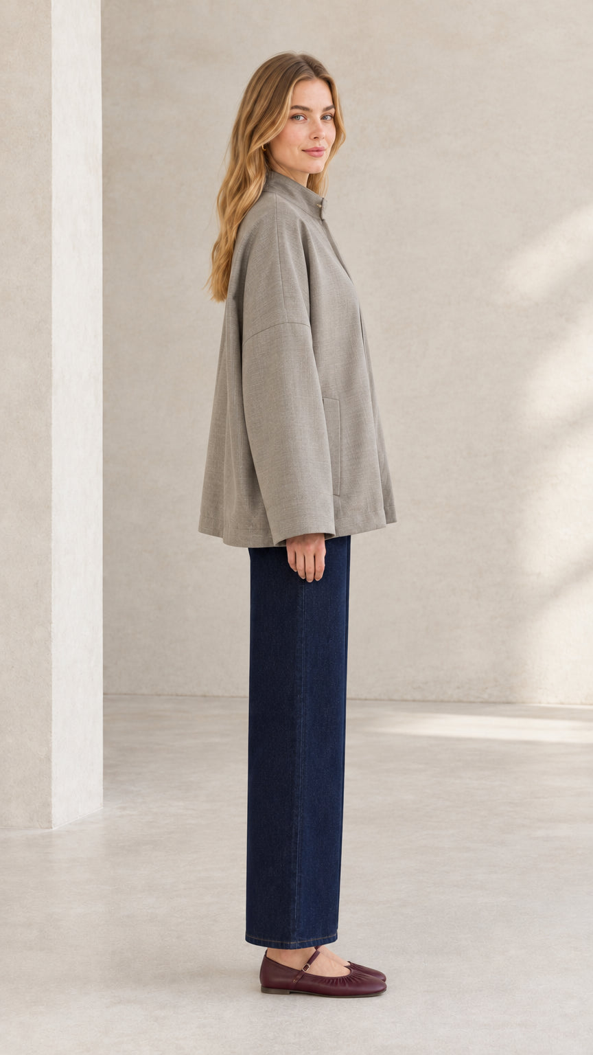 Side profile of woman modeling taupe stand collar jacket with clean swing silhouette