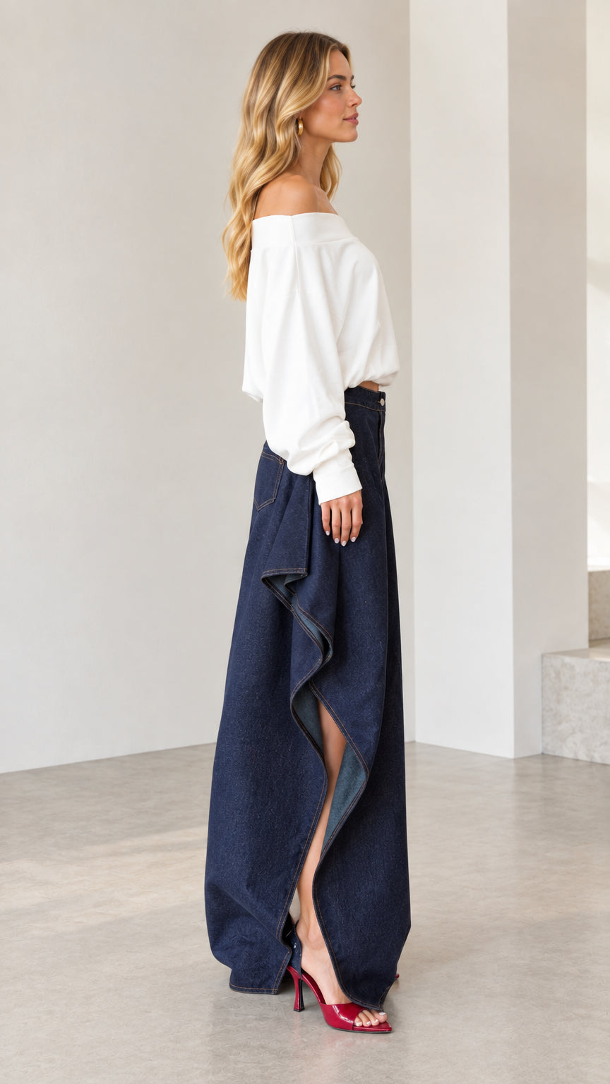 Side profile view showing dramatic cascading drape and side slit on dark blue wide-leg jeans
