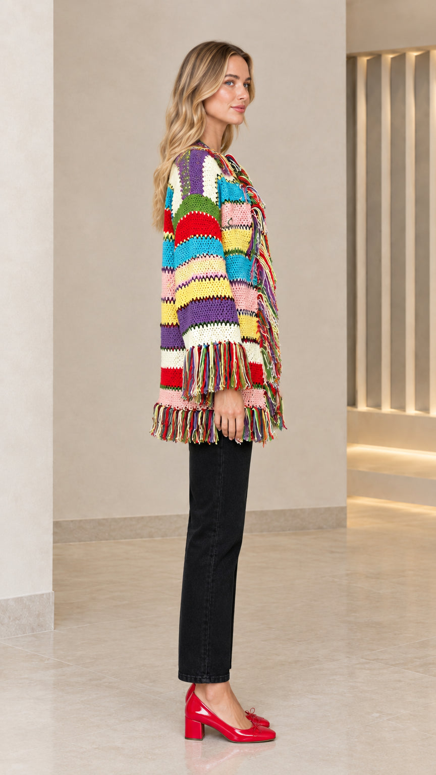Side profile view of model wearing colorful striped tassel open-front cardigan