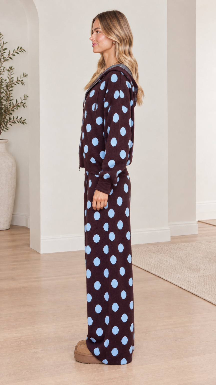 Side profile view of model wearing brown and light blue polka dot two-piece knit tracksuit