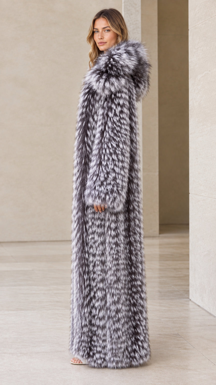 Side profile view of woman wearing long silver grey hooded faux fur coat
