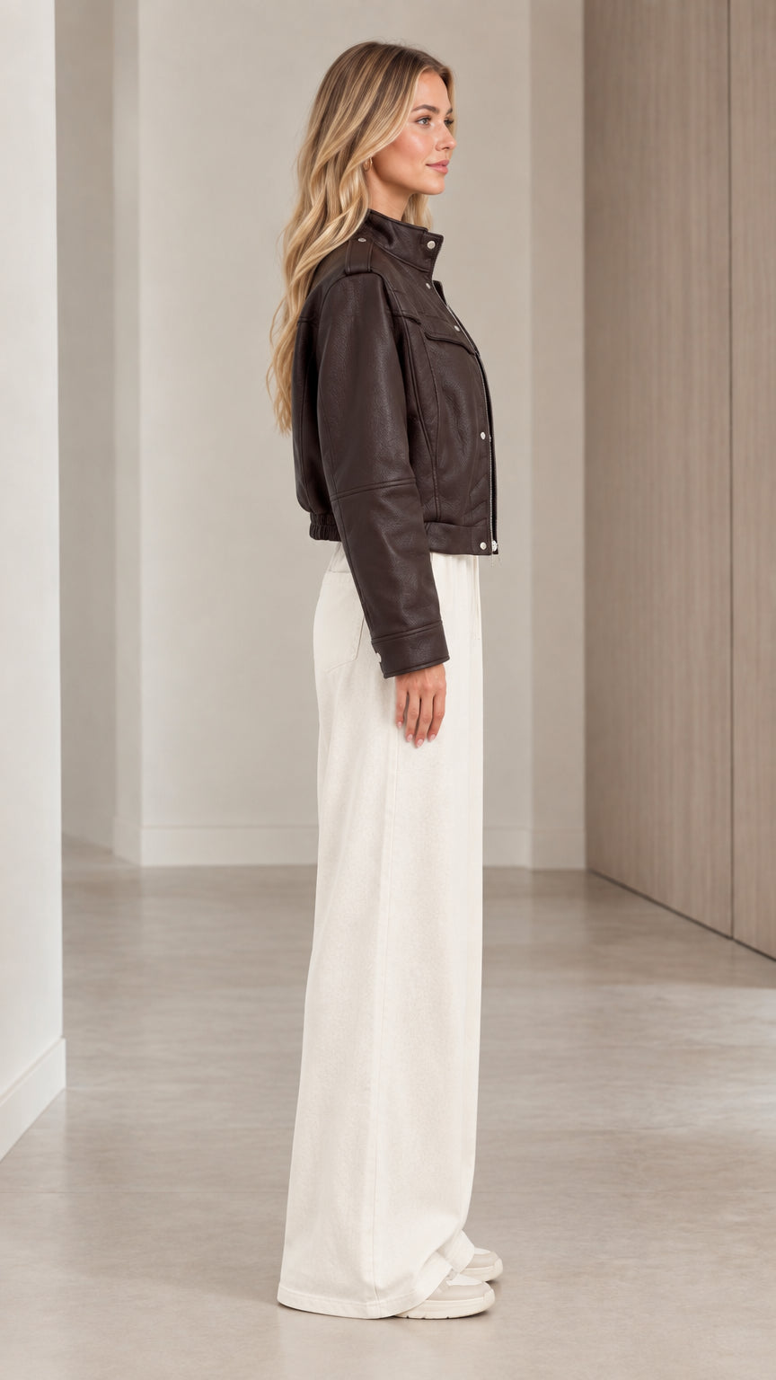 Side profile view of woman modeling the dark brown cropped faux leather jacket