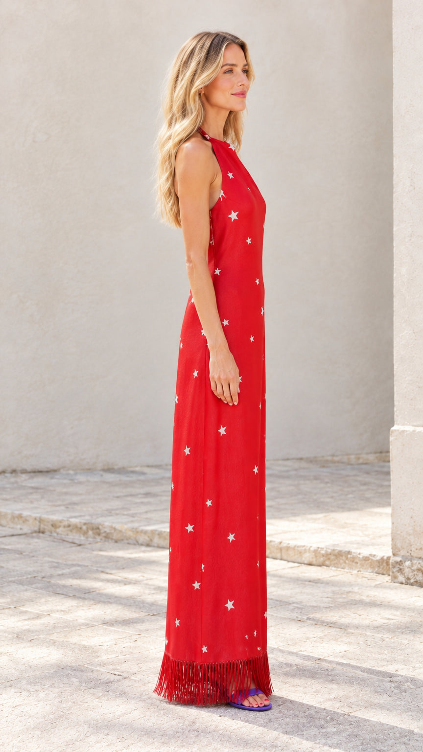Side profile view of red star print sleeveless maxi dress with fringe detail