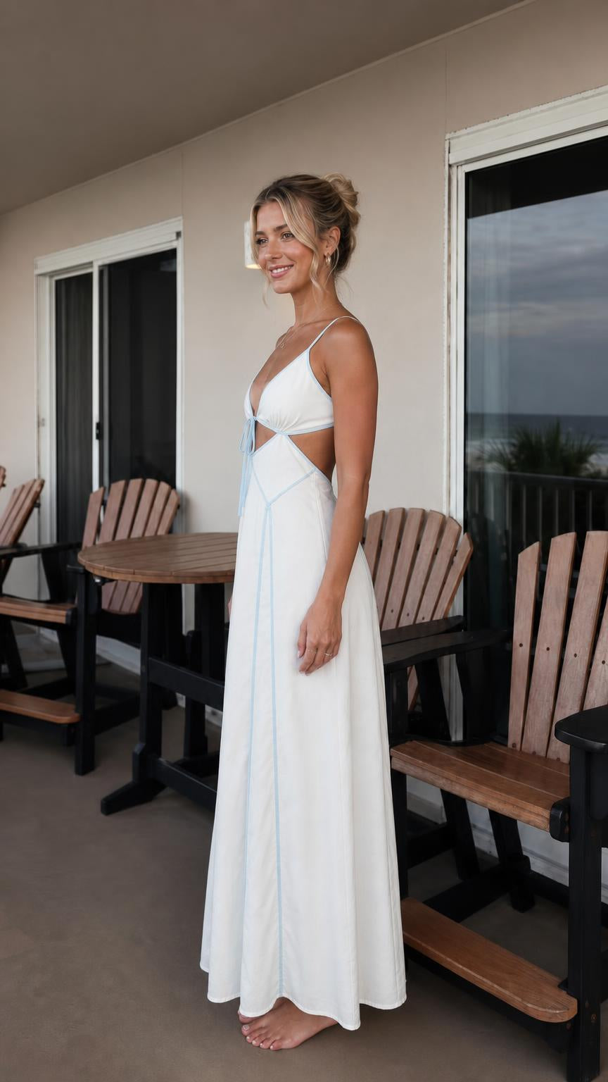Side profile view of woman in white maxi dress on balcony