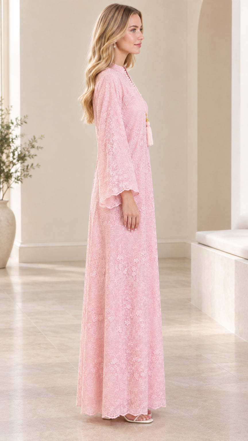 Side profile of woman wearing floor-length pink lace maxi dress with long bell sleeves