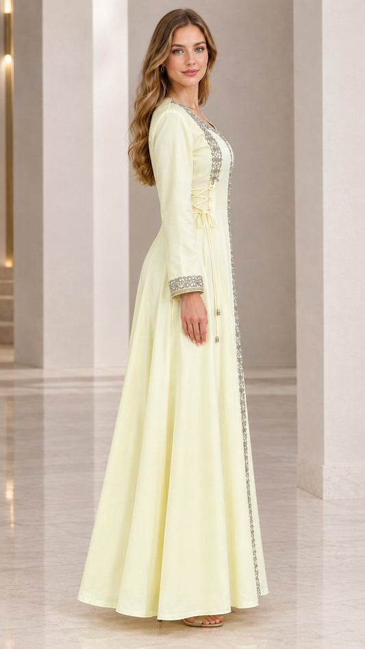 Side profile view of woman wearing pale yellow long sleeve beaded maxi gown