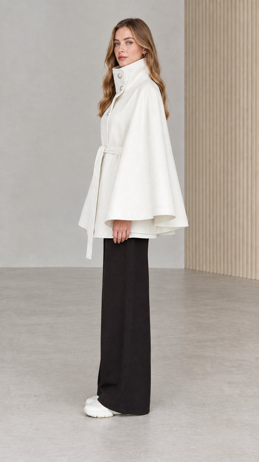 Side profile view of model wearing white stand collar belted cape coat
