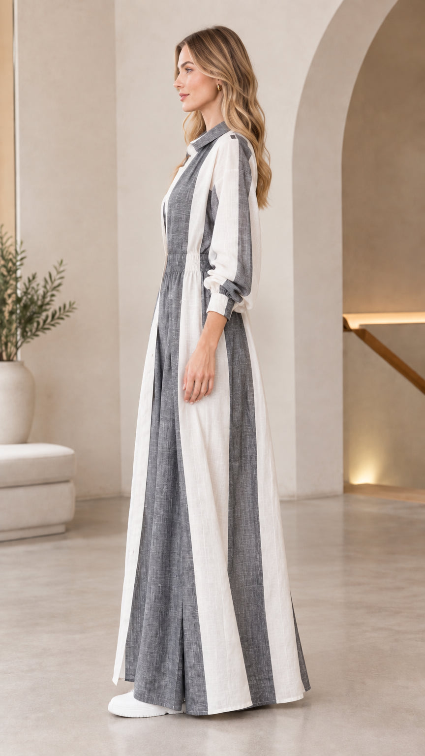 Side profile view of women's charcoal grey jumpsuit and longline striped coat
