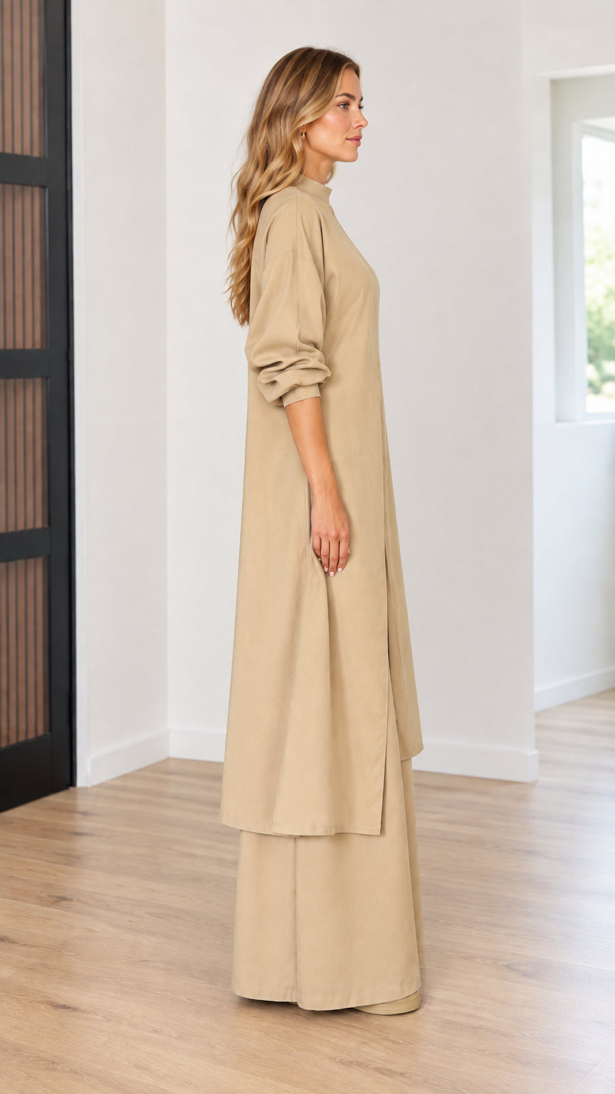 Side profile view of model wearing beige two-piece longline tunic and matching wide-leg trousers