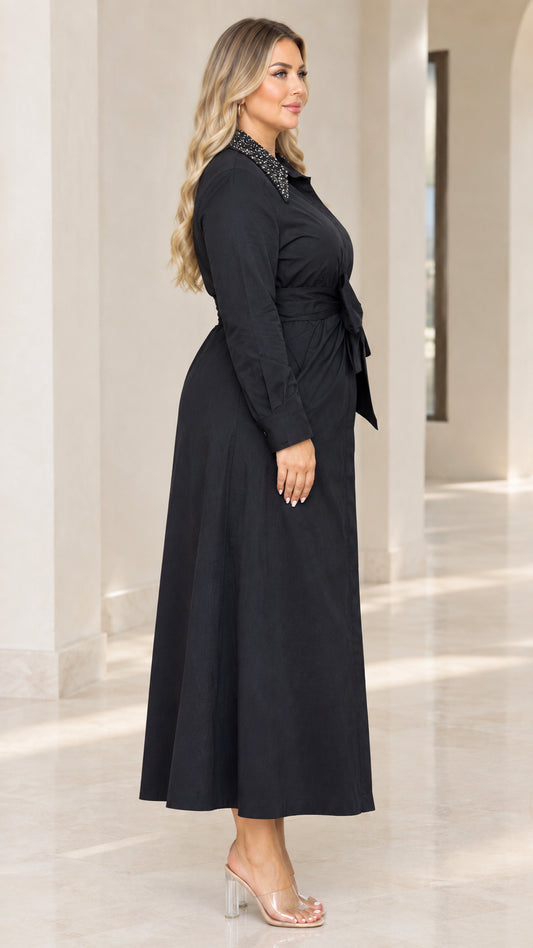 Side view of woman in black belted long sleeve maxi dress