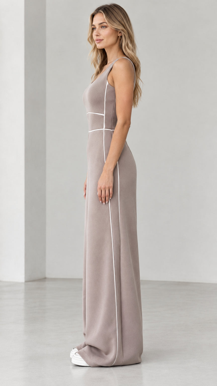 Side profile view of taupe sleeveless wide-leg jumpsuit showing contour side piping