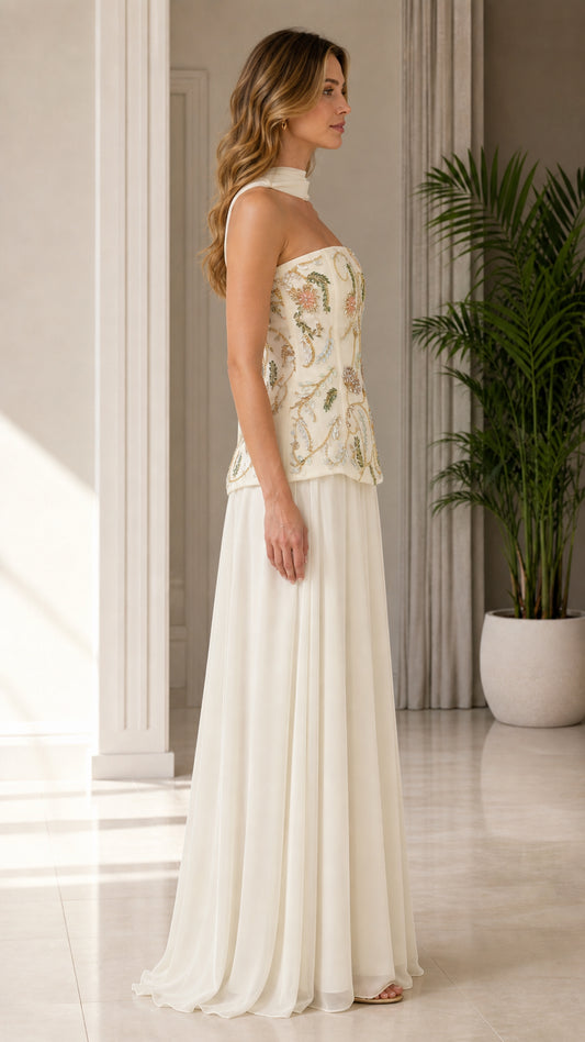 Side profile of model wearing ivory floral embroidered corset dress with flowing maxi skirt