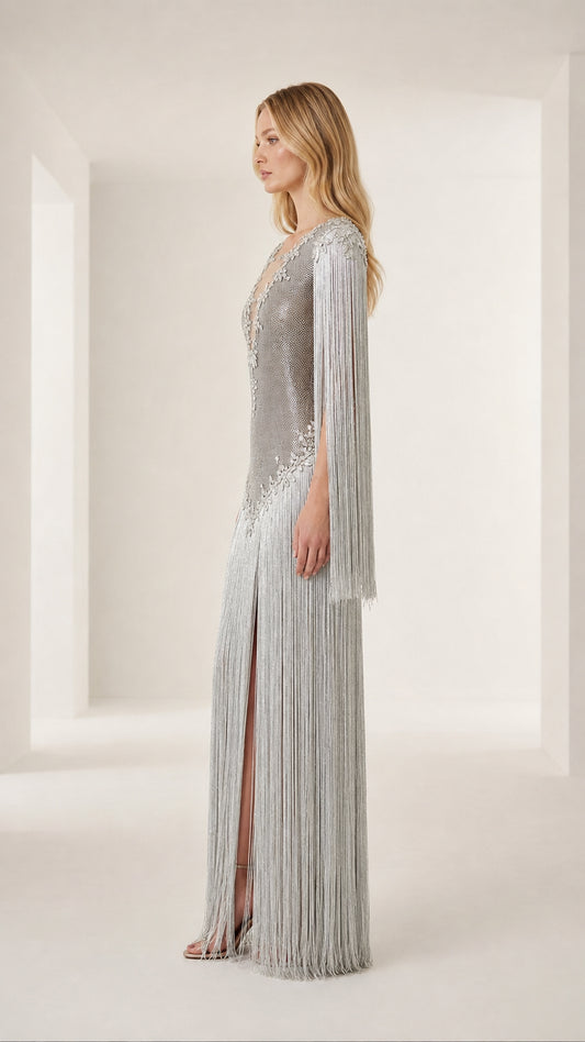 Side profile view of model in silver fringe evening dress with high leg slit