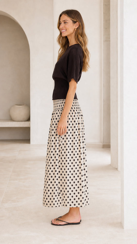 Side profile view of short sleeve black top and polka dot skirt dress in cream