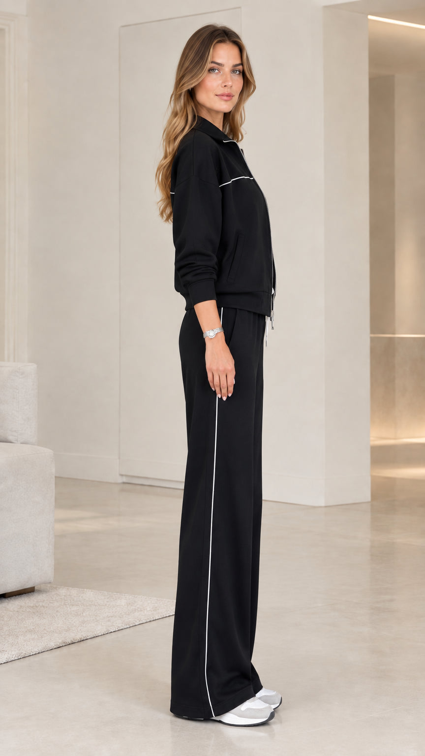 Side profile view of model wearing black two-piece wide-leg lounge track set
