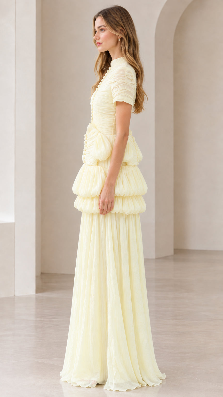 Side profile of model wearing pale yellow short-sleeve pleated evening gown