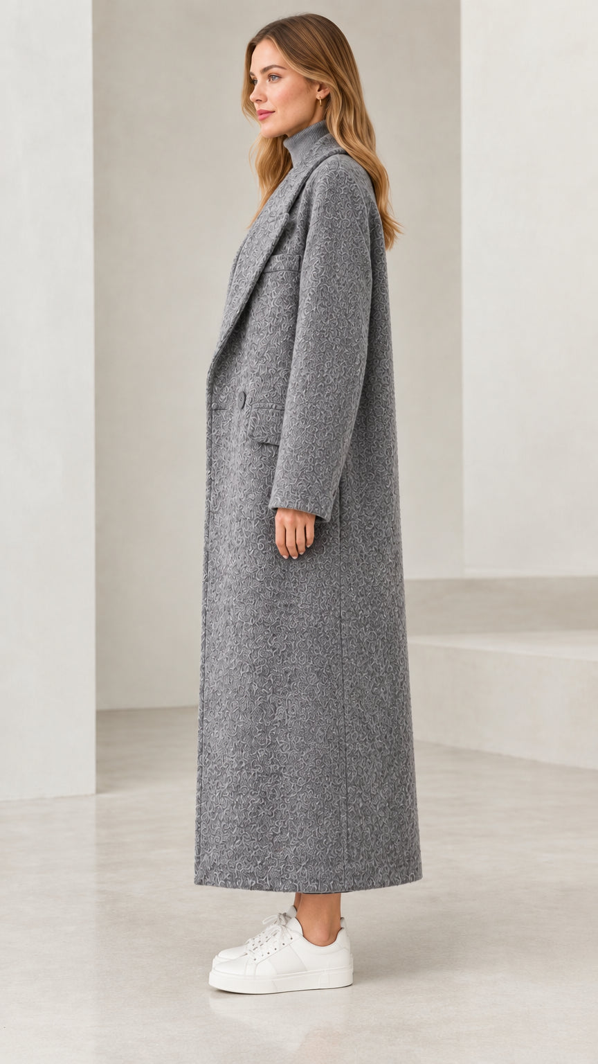 Side profile view of woman wearing long grey textured bouclé overcoat