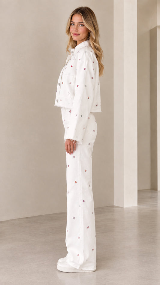 Side profile view of woman modeling white rhinestone two-piece co-ord pant set