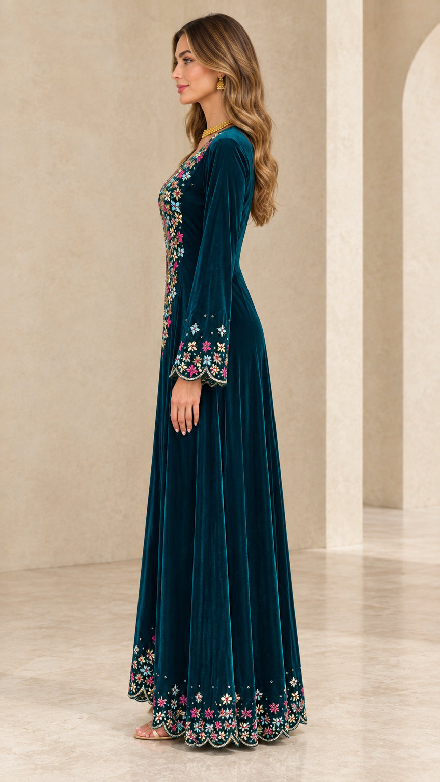 Side profile view of teal velvet long sleeve embroidered gown