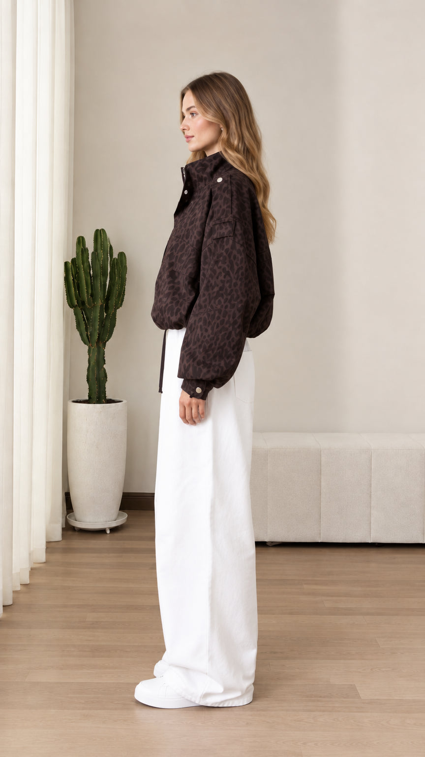 Side profile view of chocolate brown leopard print windbreaker jacket styled with white trousers