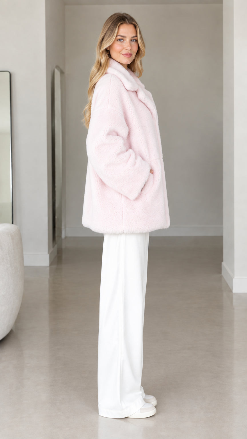 Side profile view of pale pink faux fur teddy coat with side pockets