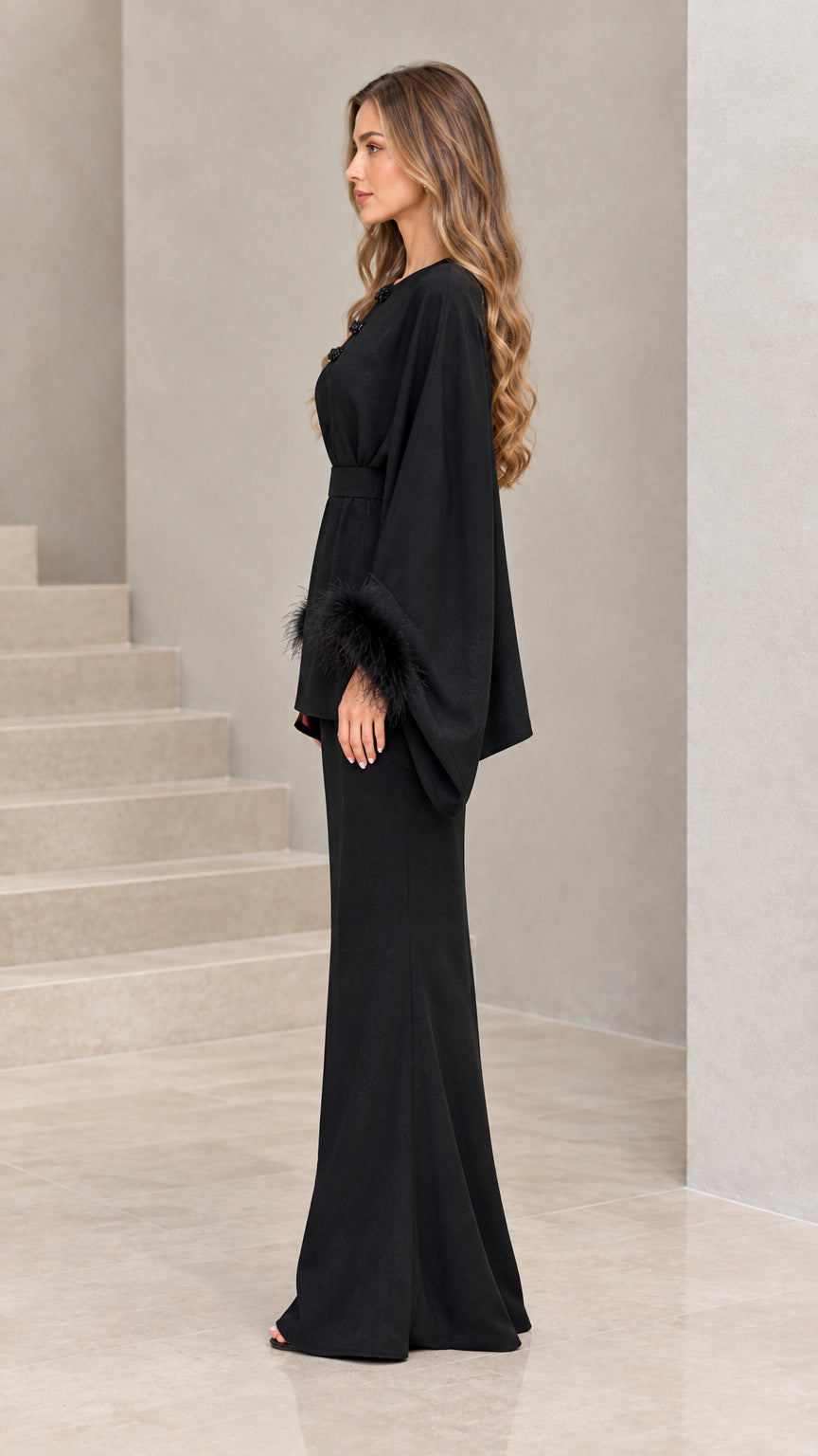 Side profile view of black draped batwing sleeve evening set with feather trim