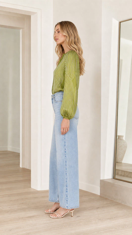 Model wearing olive striped satin blouse, side profile