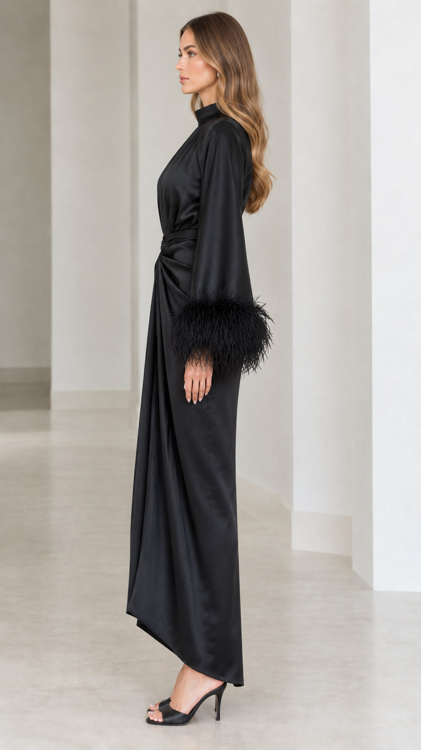 Side profile view of black satin long sleeve evening dress with feather trim