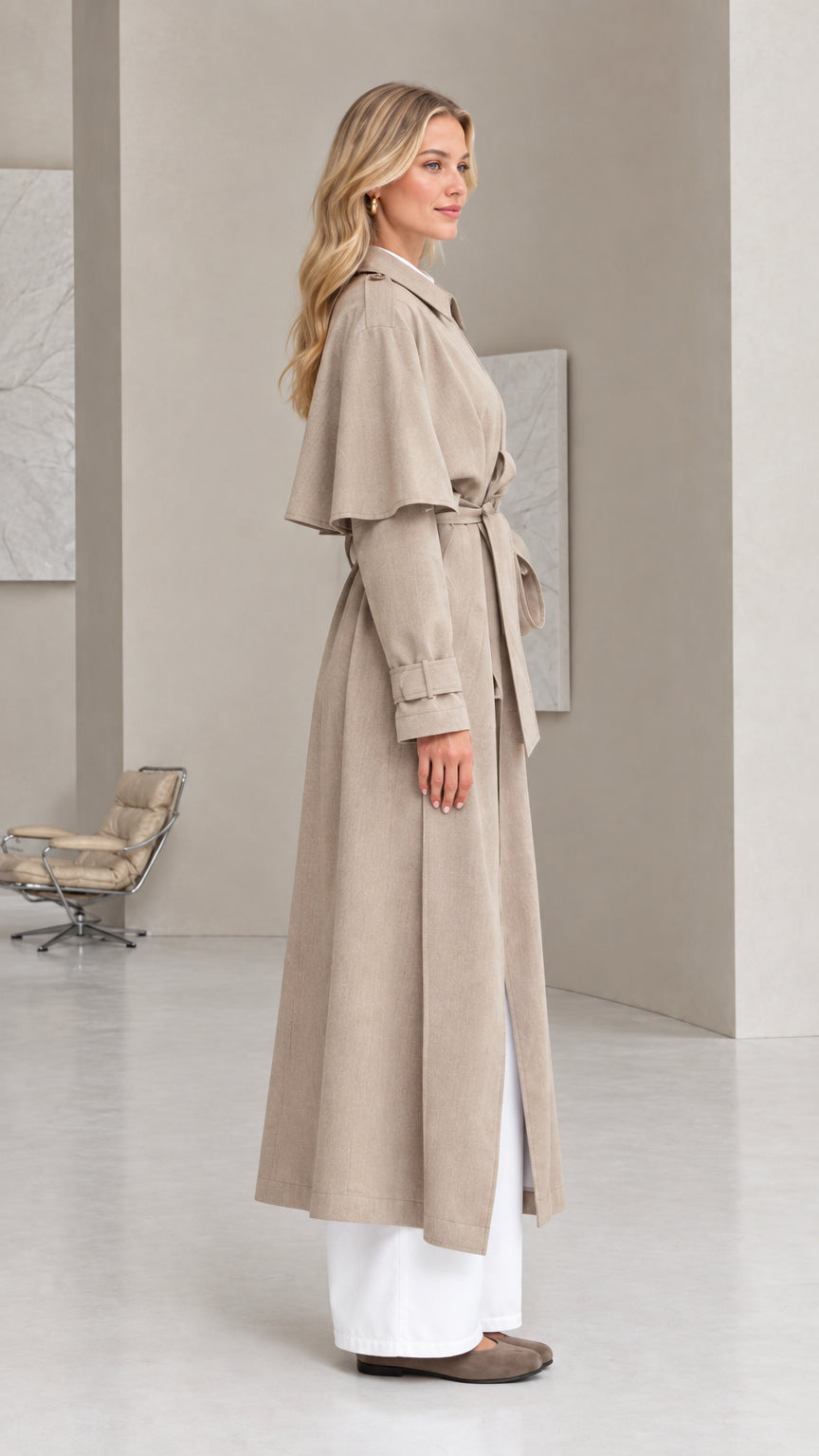 Side profile view of taupe longline cape trench coat showing shoulder overlay drape
