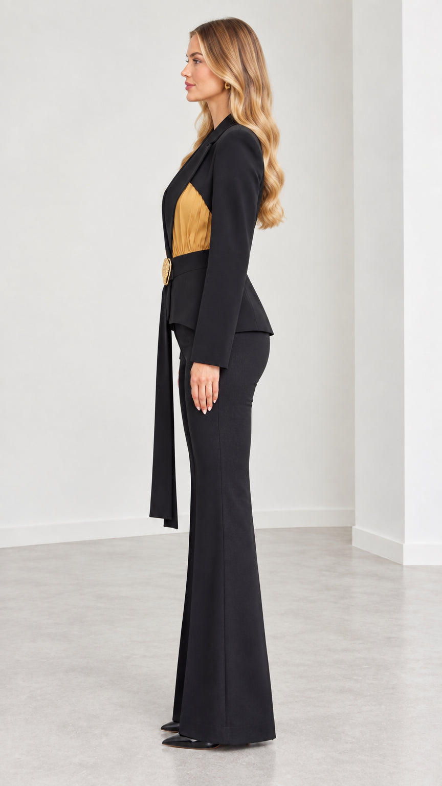 Side profile view of black belted blazer and flare leg trousers