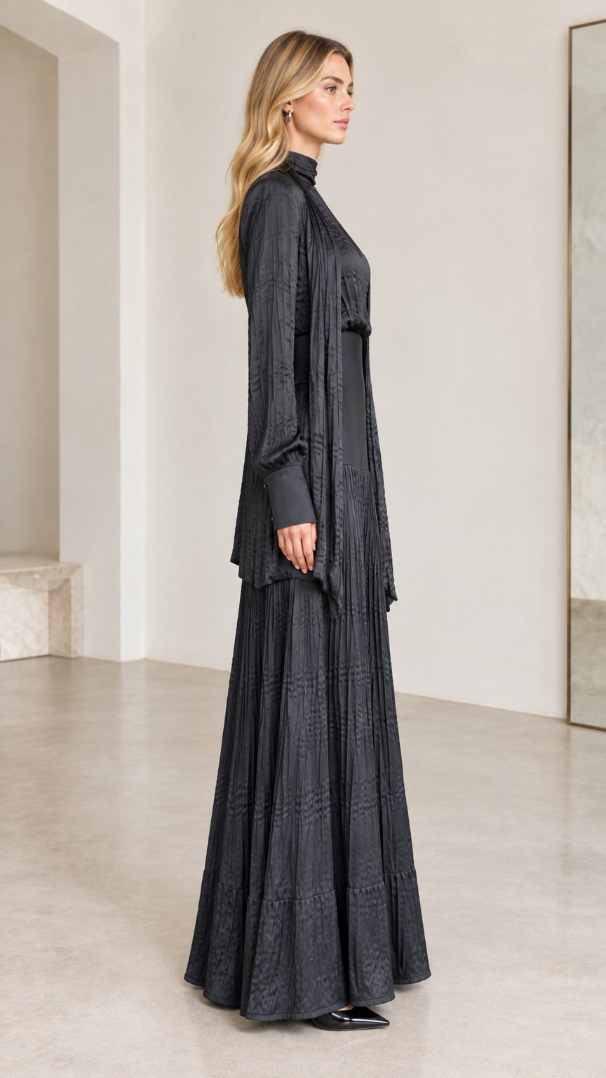 Side profile view of black mock-neck pleated maxi dress and matching long cardigan