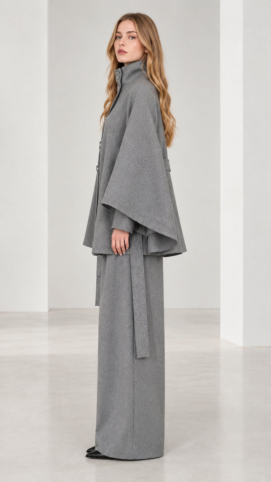 Side profile view of grey belted cape coat and flowy wide-leg trousers set