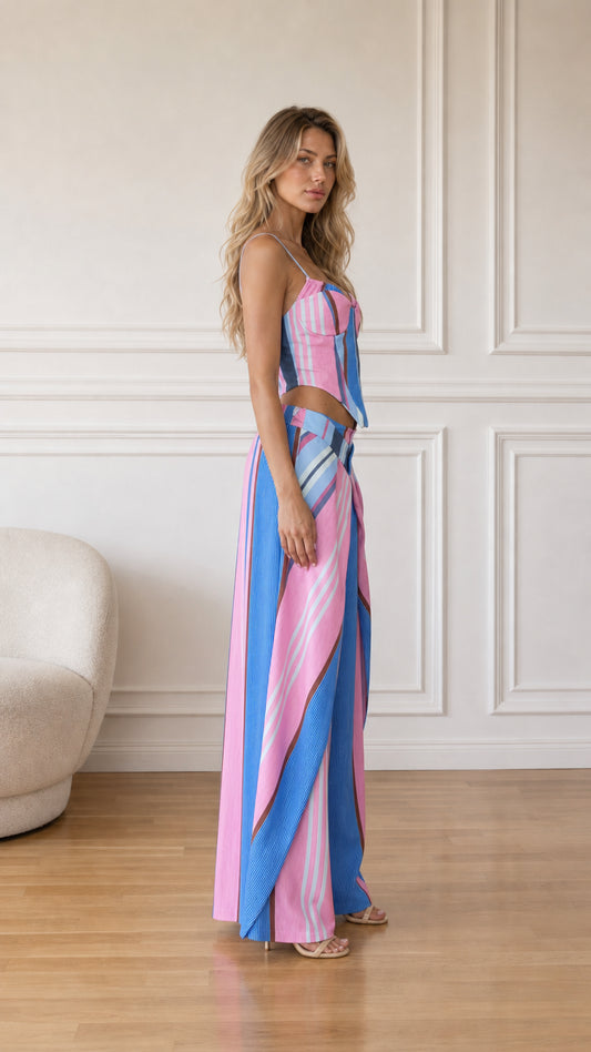 Side profile view of model wearing pink multi striped two-piece set